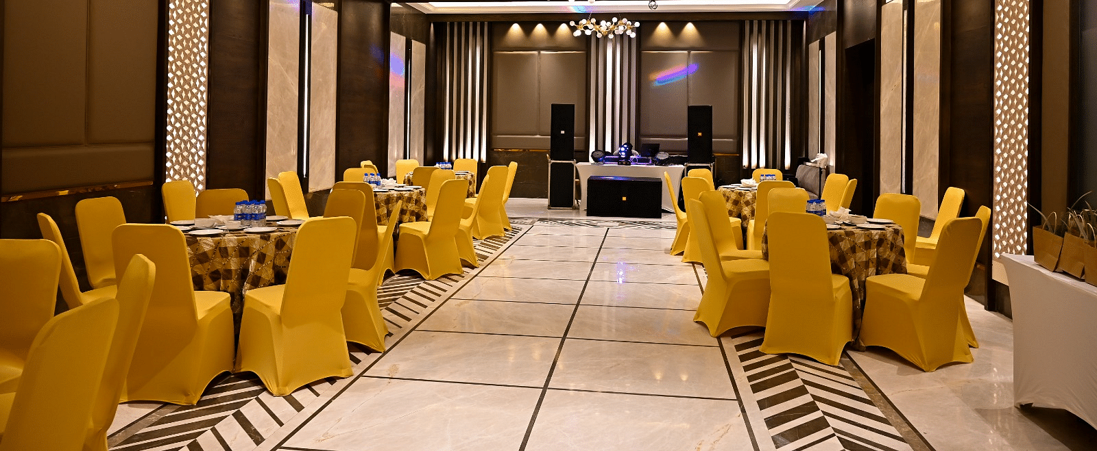 Event space with round tables and chairs arranged, featuring fancy lights hanging from the ceiling at BluSalzz Residence, Amritsar